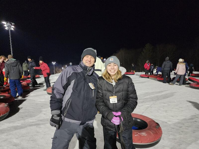 father and daughter smiling at a club tubing event